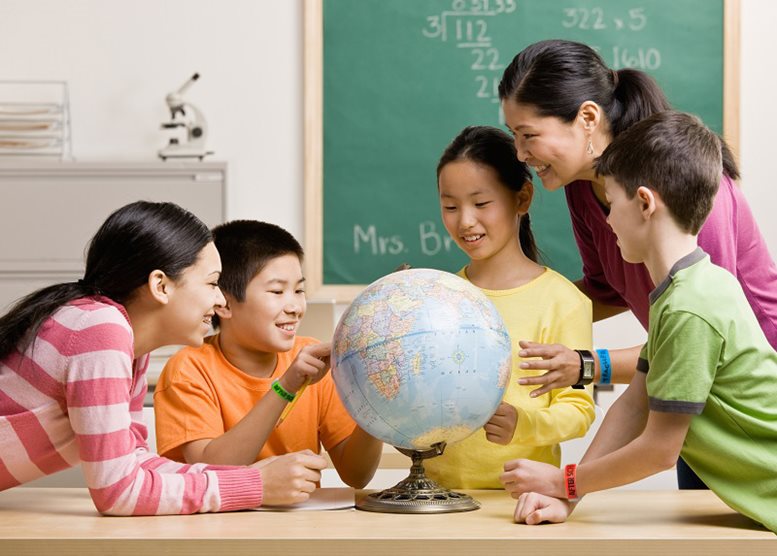 Students and a teacher wearing wristbands and looking at a globe