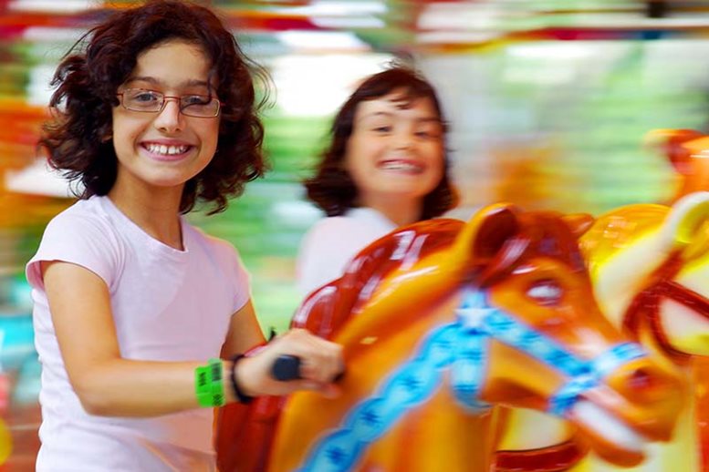 Girls wearing vinyl wristbands on carousel